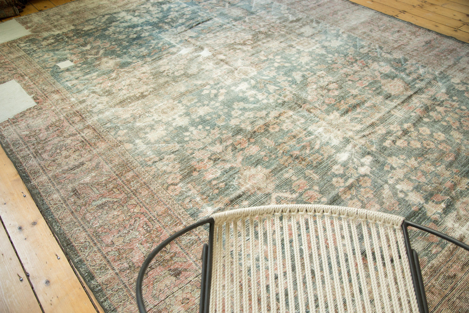 Distressed Persian Mahal rug's faded dusty teal, blush floral motifs, and mostly even wear.